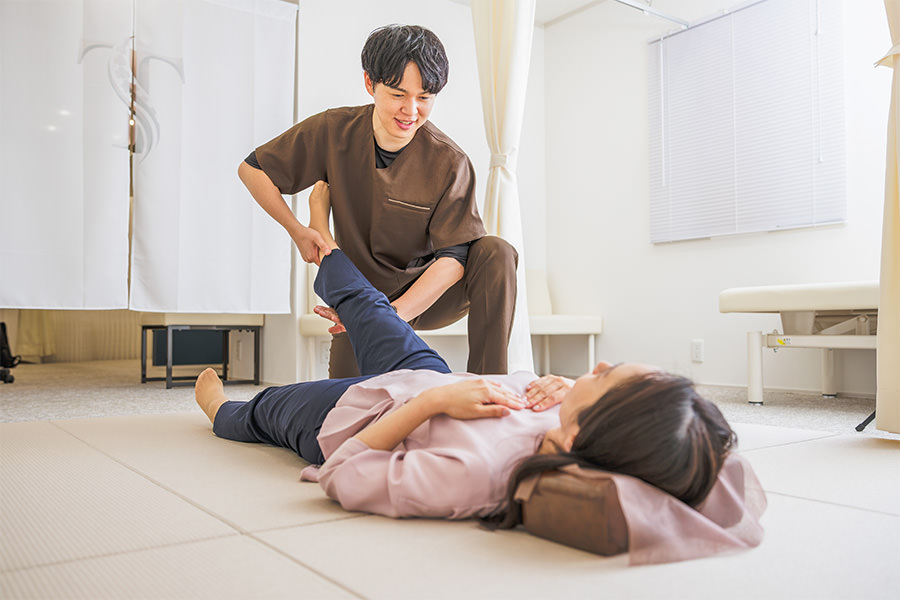 畳の上で患者さまの脚を持ち上げ、動きを確かめる院長・髙野正和