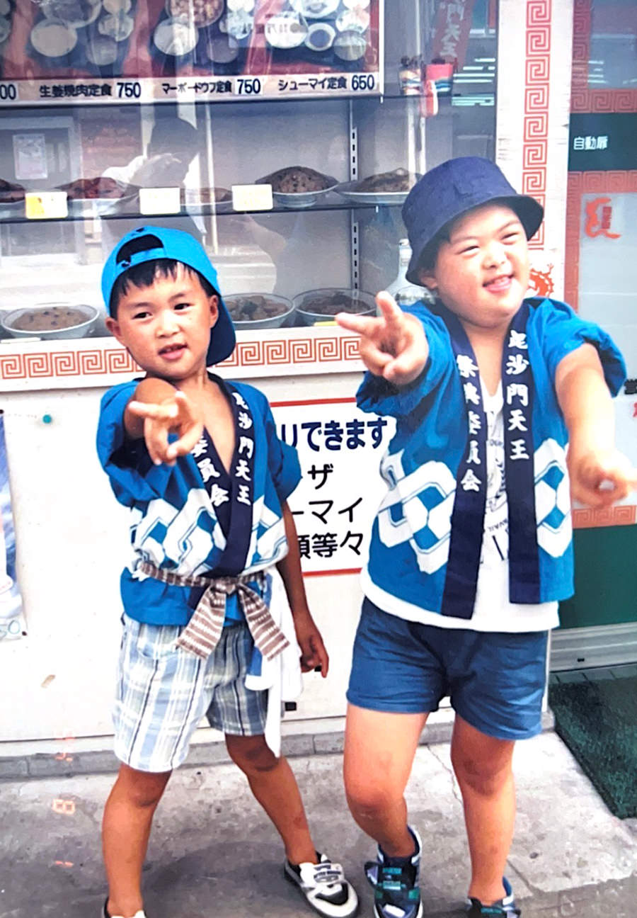 子どもの頃の写真。中華料理店の前で、祭りの法被を着た男の子2人がポーズをとっている