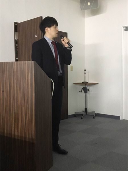 演台でマイクを持ち、研究発表をする院長