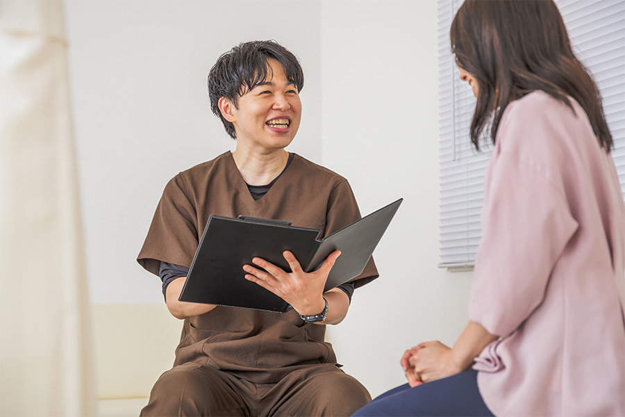 問診票を手に、患者さまと笑顔で話す院長