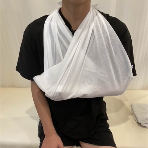 三角巾で片腕を胸の前に吊った上半身