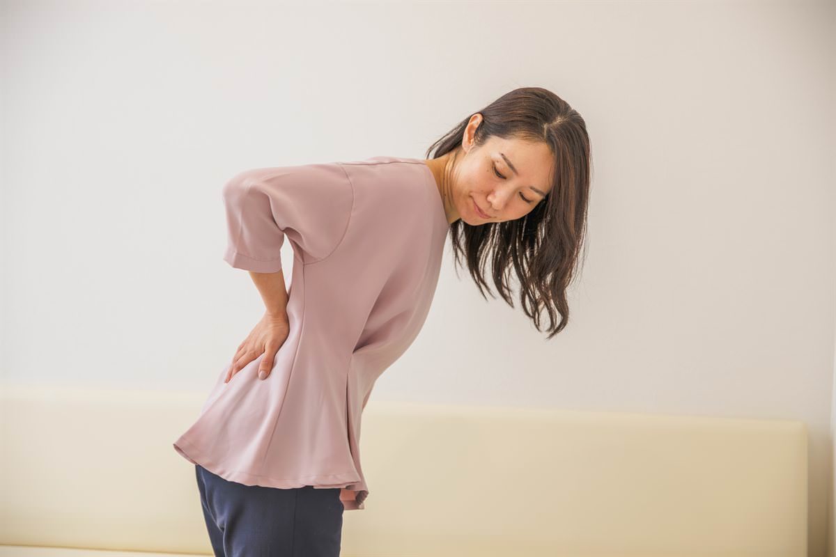 腰に手を当てて前かがみになる女性