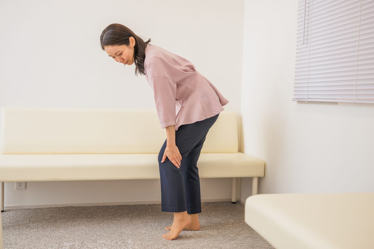 片手を膝に当て、前かがみになる女性