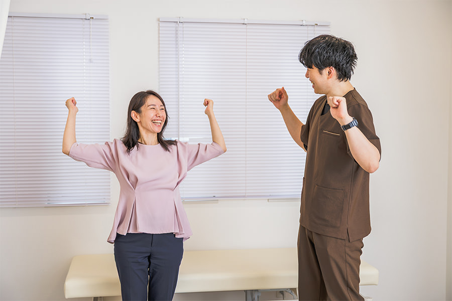 両腕を上げて力の入り方を確かめる患者さまと院長