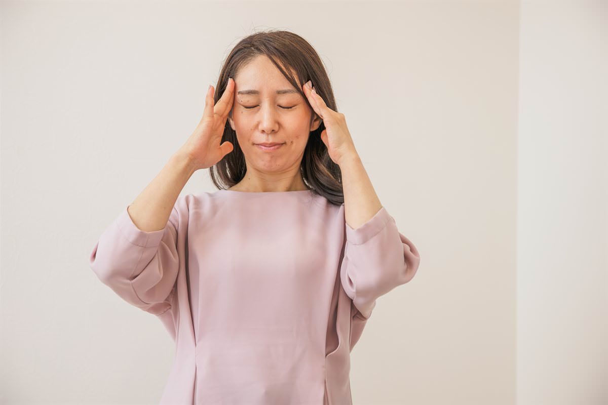 両手でこめかみを押さえる女性